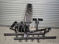 All bench components laid out including padded backrest, frame rails, roller pads, and hardware bag