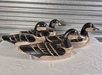 Four hand-carved wooden duck decoys side view