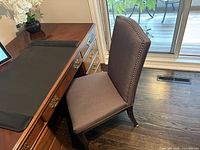 Gray fabric Parsons style armless chair positioned at wooden desk