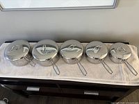 Top view of five stainless saucepans with lids