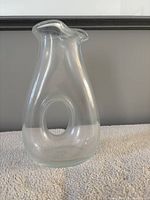 Front view showing clear glass decanter with central oval cutout and flared rim