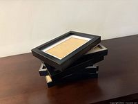 Stack of six black picture frames showing thickness and edge detail