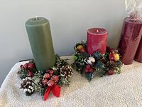 Green and red pillar candles each seated in decorative holiday rings