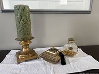 Full view of candle on holder, trinket box and glass bottle