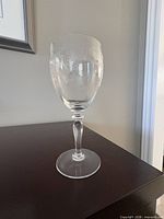 Full view of one glass showing stem, base, and etched pattern