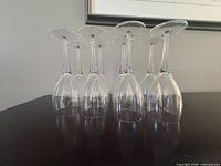 Eight clear glass stemmed flutes inverted on tabletop