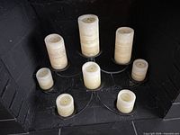 front view of fireplace opening showing eight ivory pillar candles on black metal candelabra