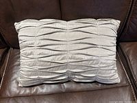 Front view of beige/taupe pleated rectangular throw pillow on brown couch