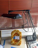 Side view of black adjustable desk lamp, cord and plug visible, plush picture frame below