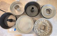 Overall view of six assorted cake pans showing three nonstick tube pans, aluminum tube pan components, textured round pan and Bundt pan