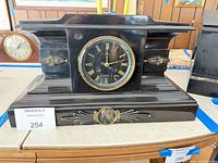 front view of black marble mantel clock showing dial and decorative elements