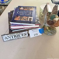 Stack of books, duck figurine, mirrored box, wooden "Antiques" sign