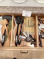 Drawer with mallet, ladles, steak knife set, measuring cups, assorted knives