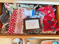 Drawer view showing multiple folded cotton fabrics in varied prints and colours plus small wood frame