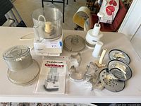 Overall lot showing food processor base, bowl, lids, blades, Zyliss chopper, discs, cookie cutters, manual