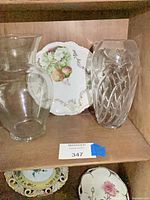 Two vases and three decorative plates displayed on shelves