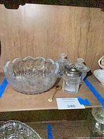 Scalloped bowl, metal spoon, glass jar with silver-plate lid, lids visible