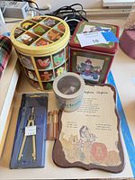 All items grouped: two decorative tins, bead tin, wooden plaque, compass set, lead boxes