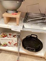 Entire lot on shelf showing boxed peeler, clamp peeler, enamel pans