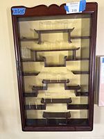 Front view of closed mahogany wall display cabinet showing glass door and tiered shelves