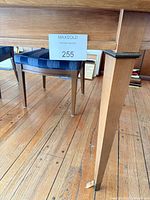 Table leg and chair seat shows wood finish and upholstery fabric