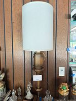 Front view of wood wall sconce with tall cream drum shade and bulb installed