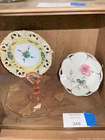 Two porcelain pieces and pink glass tray on shelf
