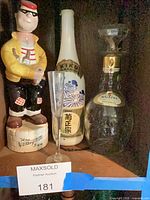 Group shot of ceramic figurine, sake bottle, champagne flute, and glass decanter.
