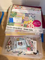 Recollections 12x12 paper pad on top of clear storage box containing loose embellishments and second box below