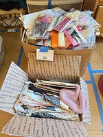 Two boxes filled with sewing patterns, ribbons, trims, embroidery floss, fabric scraps