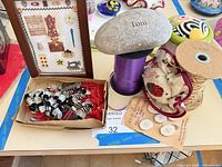 Overall lot showing framed collage, bee pins, ribbon spools, pincushions and stone paperweight