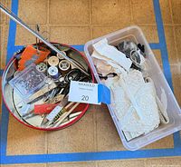 Overview of metal tray with scissors, pins, tools and adjacent bin of lace and elastic