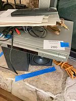 Overall lot showing DVD/VHS combo, speaker, remote, cables, manuals