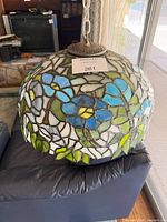 Close view of stained glass shade showing blue floral pattern and metal top cap