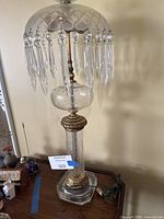 Full view of lamp showing cut crystal shade, hanging prisms, etched glass column and brass accents