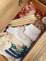 Drawer view showing doilies, handkerchiefs, candles, napkin rings