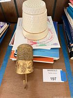 Brass wall hook, ceramic trinket box and stack of thimble books together