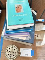 Stack of thimble reference books and one metal thimble holder visible