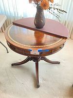 Full view of round leather-top Weiman table with vase and half-moon pad on surface