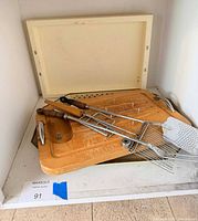 Group shot on shelf: plastic tray liner, wood carving board, skewers, spatula, cone