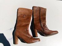 Side view of both brown leather knee-high boots showing zipper, heel and shaft