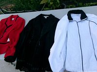 Overview of three jackets laid out: red knit, black suede-like, white quilted
