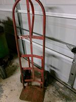 Front view of red metal hand truck showing frame and toe plate