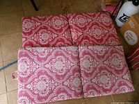 Four rectangular panels forming two hinged cushions with red white paisley fabric; ties visible