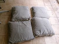 Four square light grey chair cushions laid out on tiled floor, showing overall appearance
