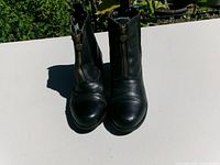 Front view of the pair of black leather boots showing toe shape and zippers