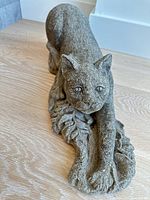 Front angle of stone cat statue showing facial detail and extended paw