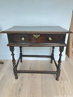 Full front view of oak side table showing drawer, legs, and stretcher