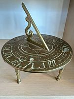 Top perspective of brass sundial showing dial face, gnomon and legs