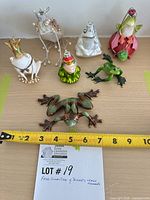 Group shot of ceramic frog figurine and five frog ornaments with tape measure for scale